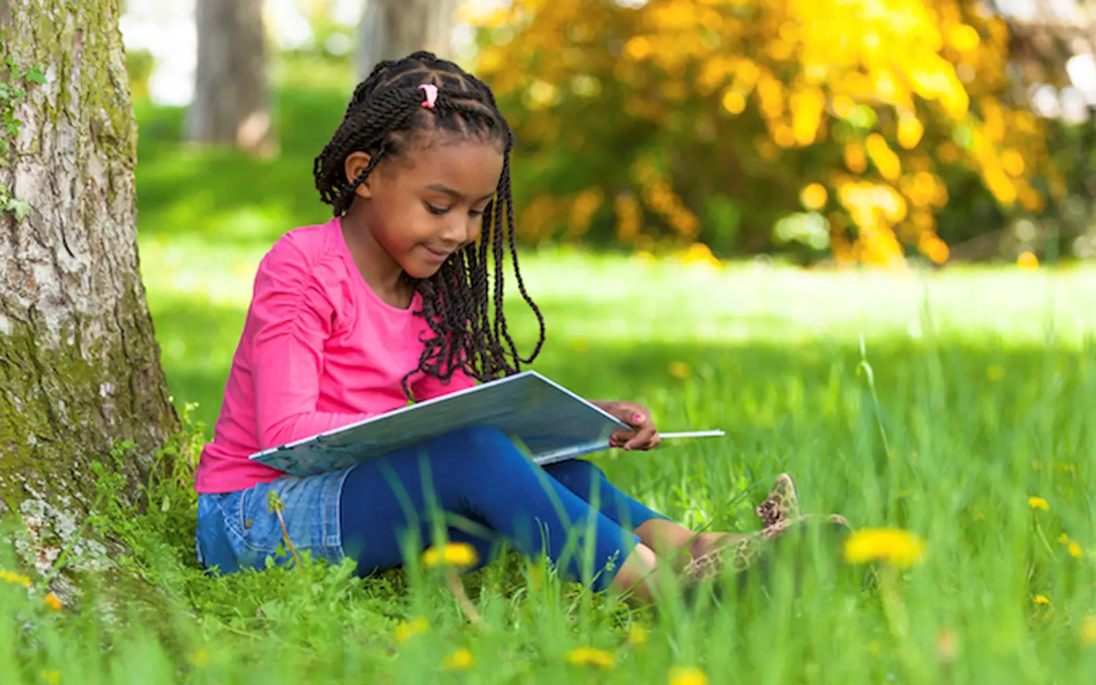 Child Reading Book Under Tree