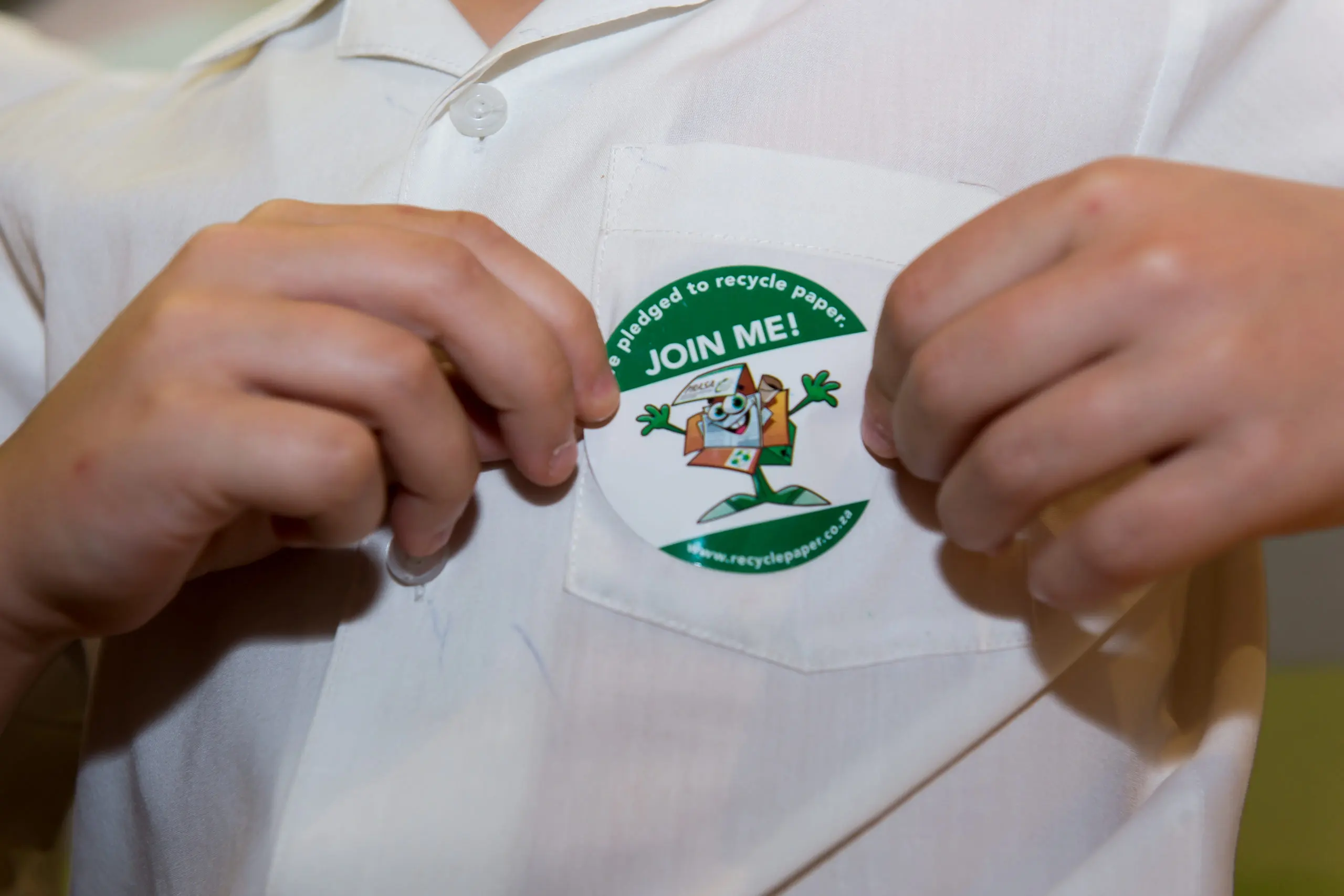 child placing recycle pledge sticker on shirt