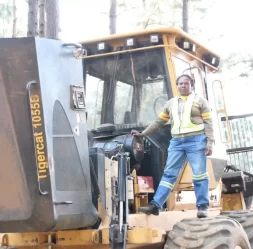 forestry worker standing on tigercat machine