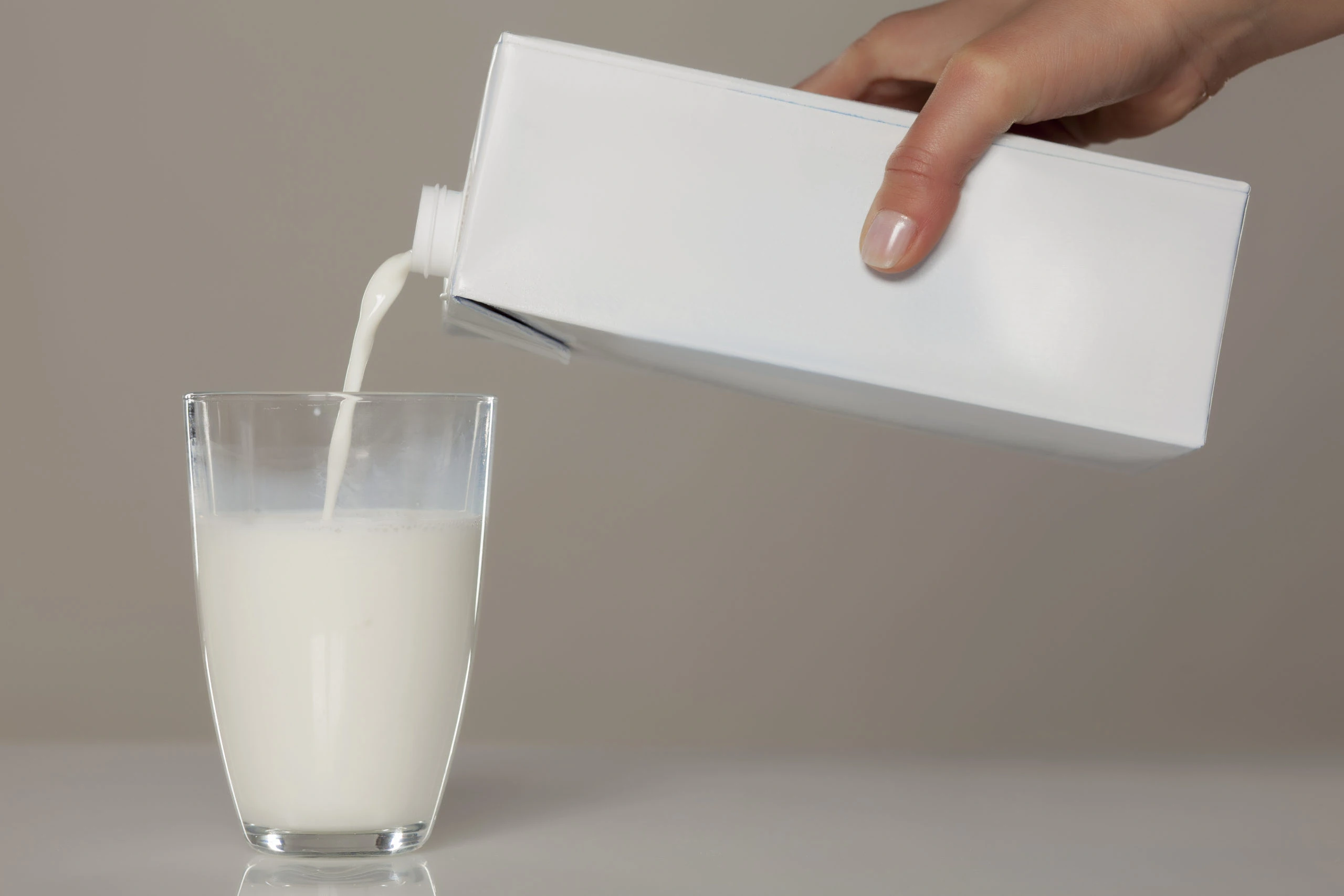 milk being poured from carton into glass