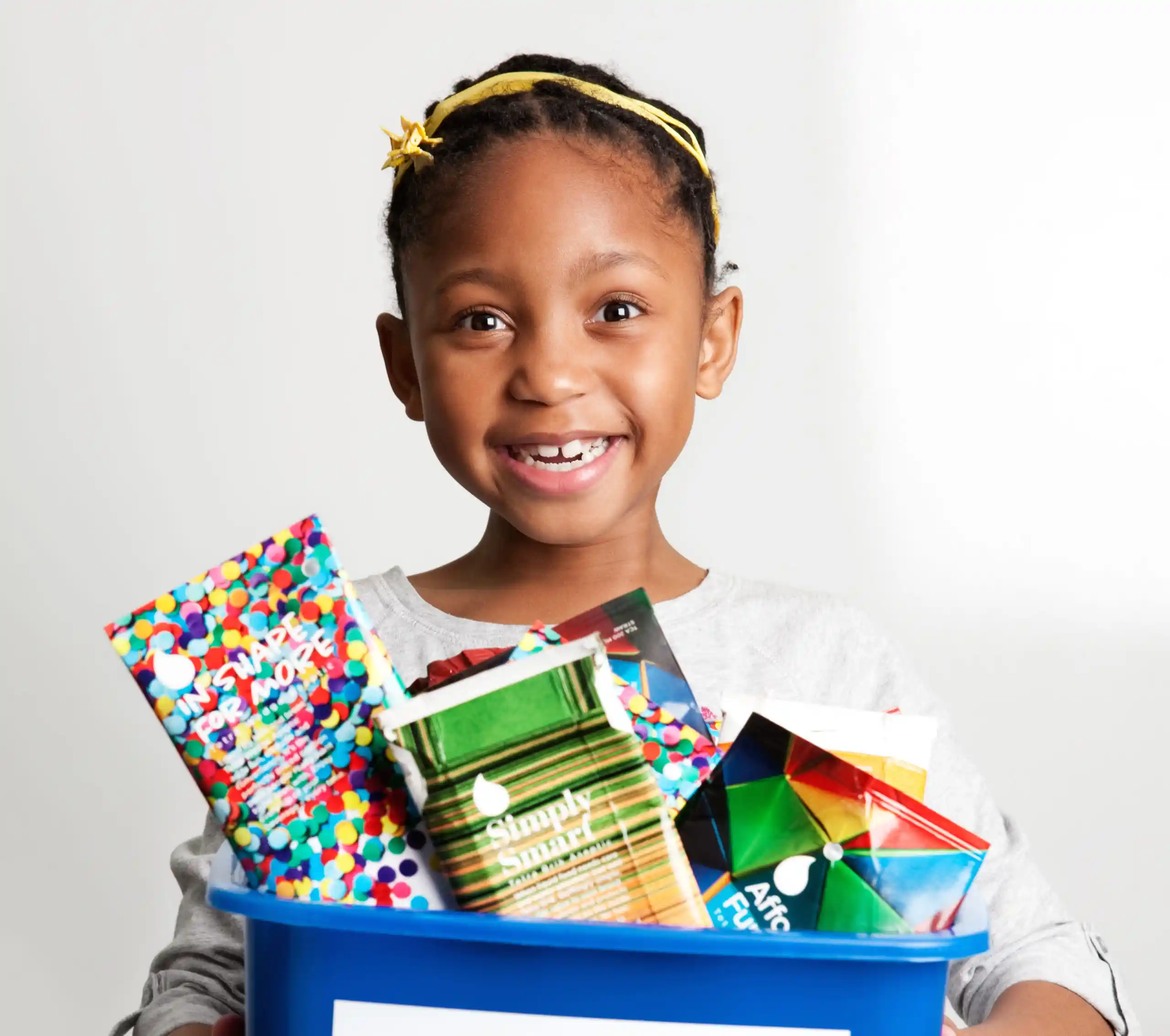 smiling child holding bin of colourful cartons