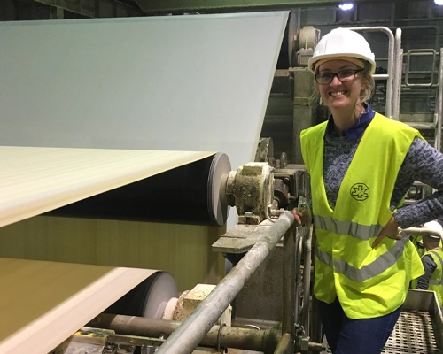 worker inspecting large paper production machine
